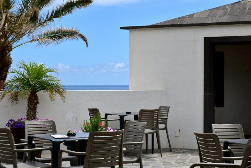 a patio with a table and chairs and a view of the ocean